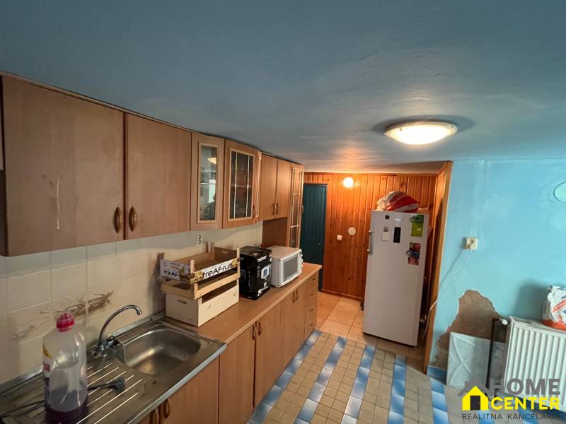 Eine Küche in einem Einfamilienhaus mit Holzschränken, einer Mikrowelle und einem Kühlschrank.