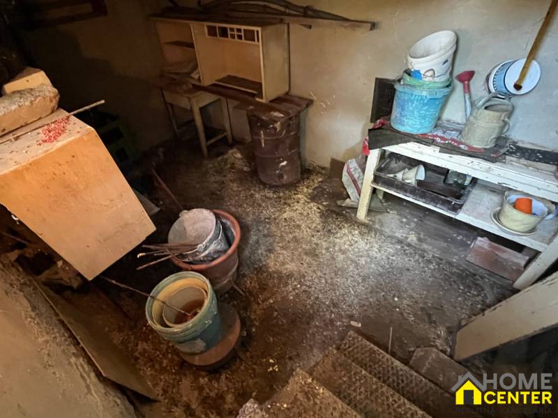 Alter Keller eines Einfamilienhauses mit einem Tisch, Eimern und Werkzeugen in einem dunklen Raum.