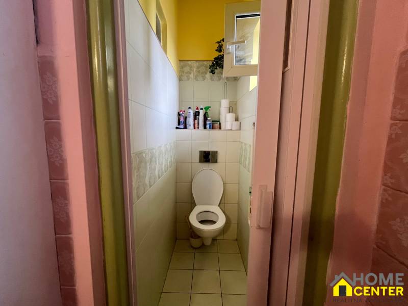 Badezimmer in einem Einfamilienhaus mit Toilette und Regal mit Reinigungsmitteln.