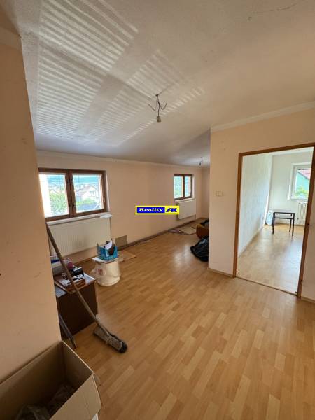 Ein Zimmer mit Holzboden und Fenstern in einem Einfamilienhaus, bereit für die Renovierung.