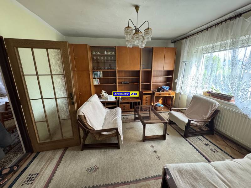 Wohnzimmer in einem Einfamilienhaus mit Sofas, Holzmöbeln und einem großen Fenster.