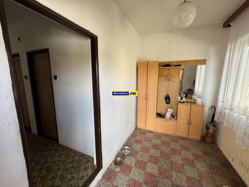 Der Flur eines Einfamilienhauses mit einem Korb aus Weidengeflecht, einem Schrank und Vorhängen.