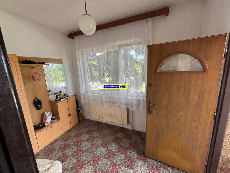 Innenraum eines Einfamilienhauses mit Flur, Eingangstür und Fenster mit weißem Vorhang.