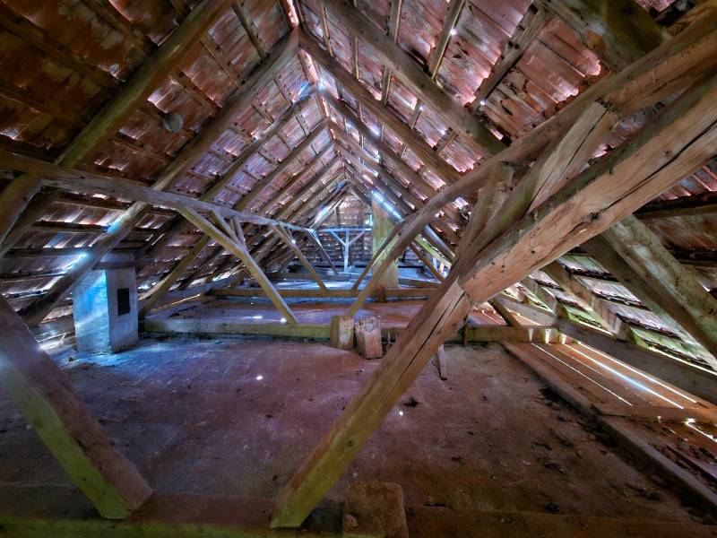 Das Dachgeschoss eines Einfamilienhauses mit Holzbalken und einem erhaltenen Ziegeldachsystem.