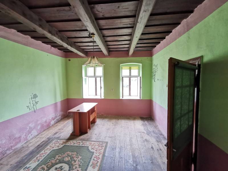 Ein Zimmer in einem Einfamilienhaus mit einer Holzdecke, einem alten Tisch und einem Teppich.