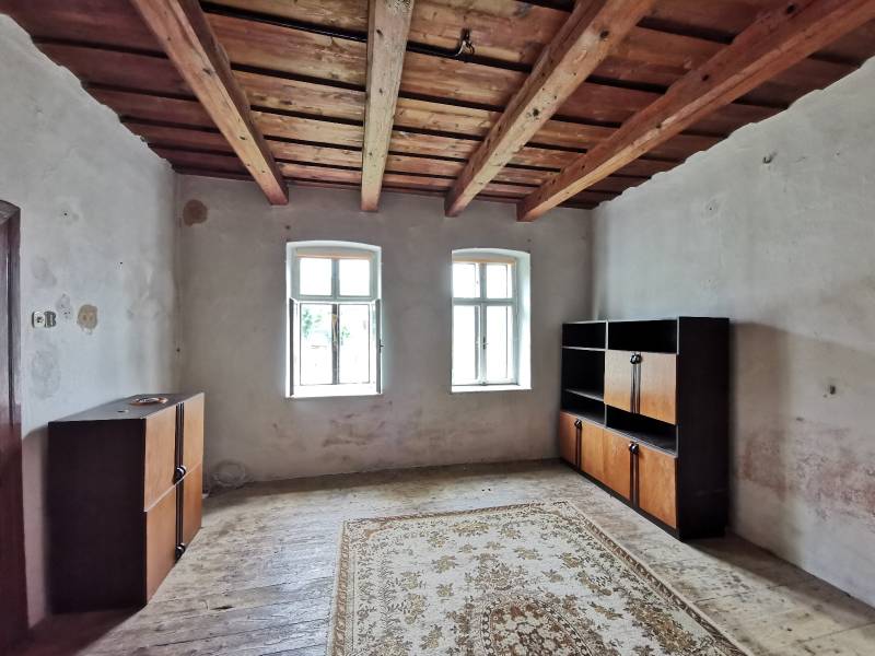 Ein Zimmer in einem Einfamilienhaus mit Holzdecke, Fenster, Schränke, Teppich auf dem Boden.