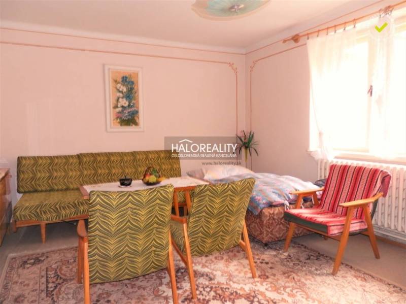 Wohnzimmer in einem Einfamilienhaus, Vintage-Möbel, Teppich, helle Wände, großes Fenster.