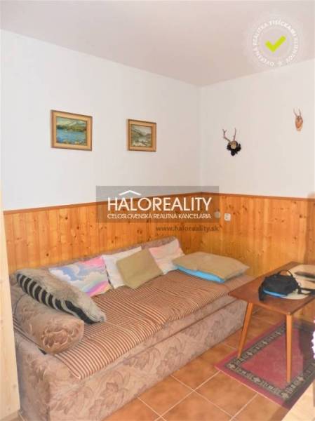 Innenraum eines Einfamilienhauses mit Sofa, Bildern an der Wand und Holzverkleidung.