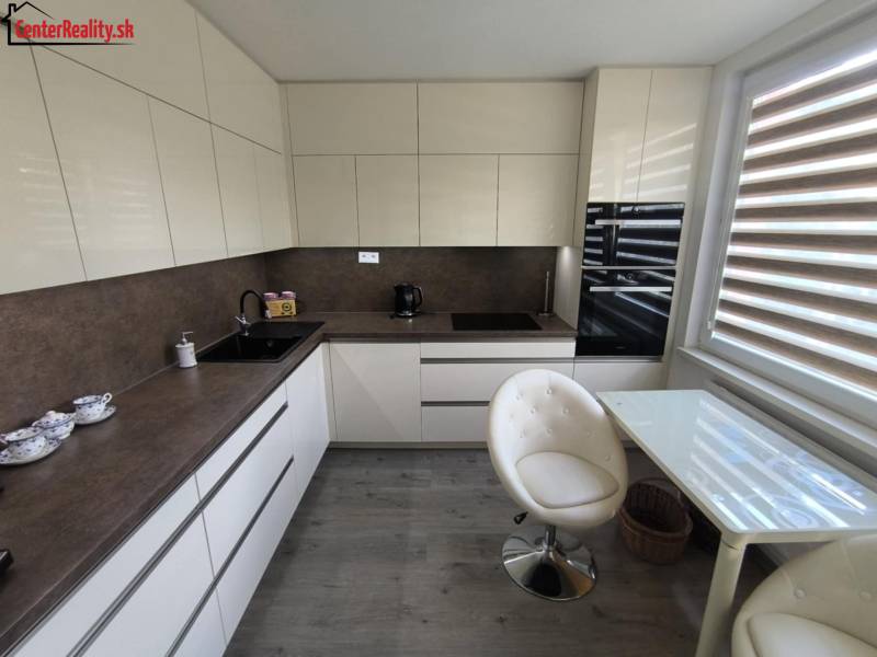 Küche in einer 3-Zimmer-Wohnung mit hellen Möbeln, Glastisch und zwei Stühlen.