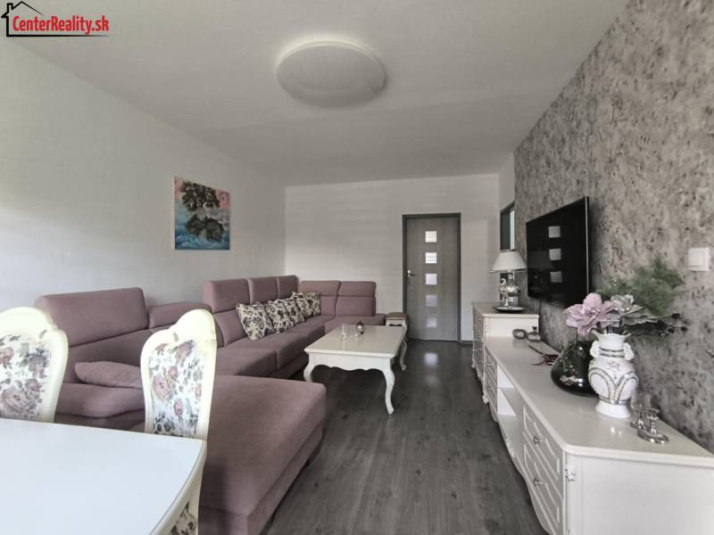 Wohnzimmer in einer 3-Zimmer-Wohnung, mit einem Sofa, dekorativen Möbeln und einem Fernseher an der Wand.