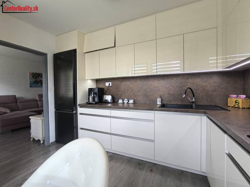 Eine Küche in einer 3-Zimmer-Wohnung mit moderner Ausstattung und angrenzendem Wohnzimmer, helle Farbtöne.