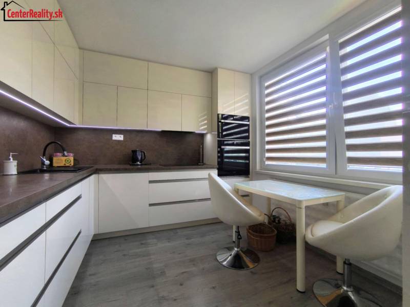 Küche in einer 3-Zimmer-Wohnung mit Sitzgelegenheit und großem Fenster mit Jalousien.