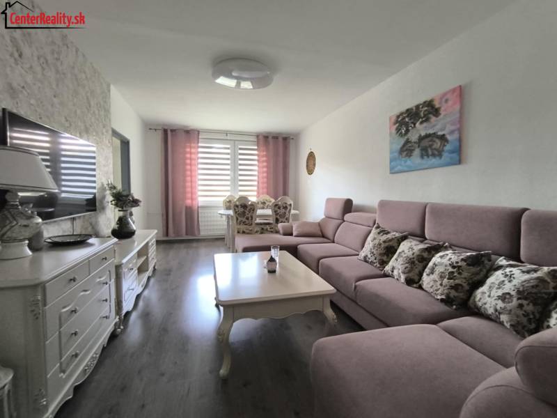 Wohnzimmer mit Sofa und Tisch in einer 3-Zimmer-Wohnung, helle Wände, Fernseher auf dem Schrank.