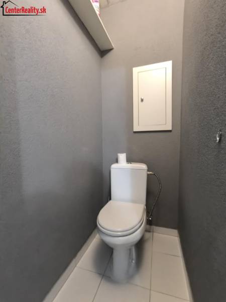 Graues Badezimmer mit Toilette und Regal in einer 3-Zimmer-Wohnung.