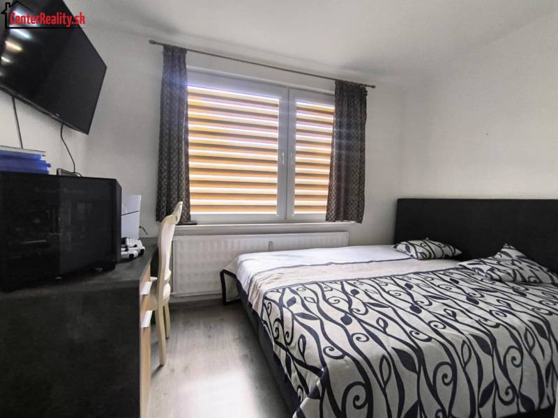 Schlafzimmer mit Bett, Fernseher und Schreibtisch in einer 3-Zimmer-Wohnung.