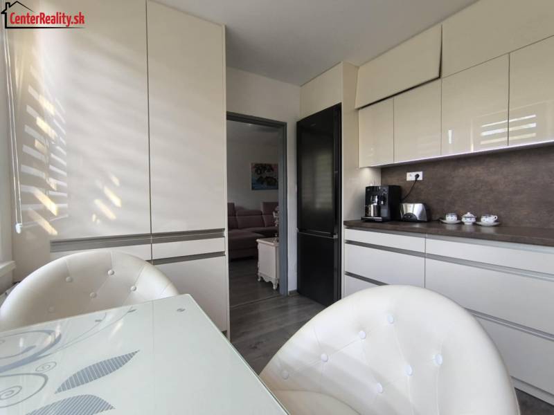 Küche in einer 3-Zimmer-Wohnung mit weißen Schränken und einem Esstisch.