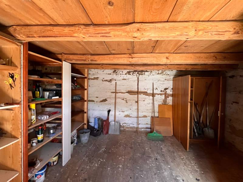 Holzinterieur eines Einfamilienhauses mit Regalen für Werkzeuge und einer Holzdecke.