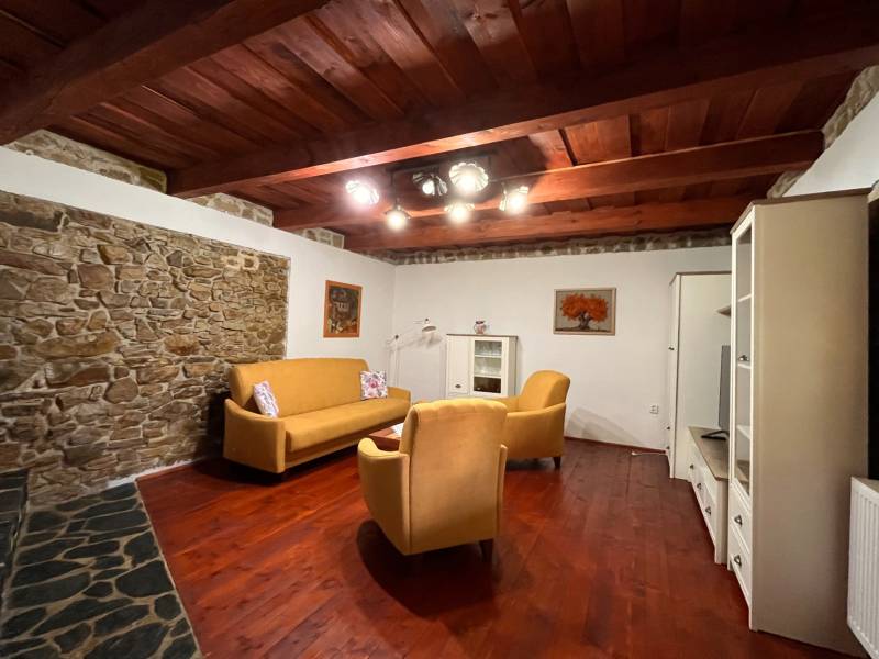 Wohnzimmer eines Einfamilienhauses mit Steinwand, Holzbalkendecke und bequemen Möbeln.