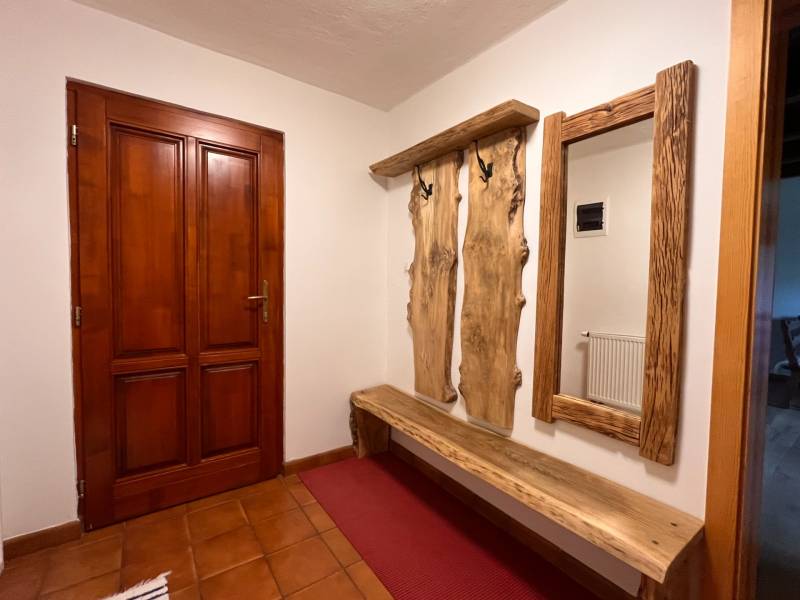 Holzbank und Kleiderständer mit natürlichem Spiegel im Innenraum eines Einfamilienhauses.