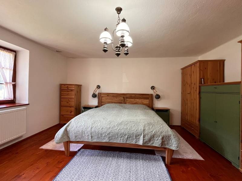 Ein Schlafzimmer in einem Einfamilienhaus mit Holzmöbeln und einem Bett, Deckenleuchte, Holzboden.