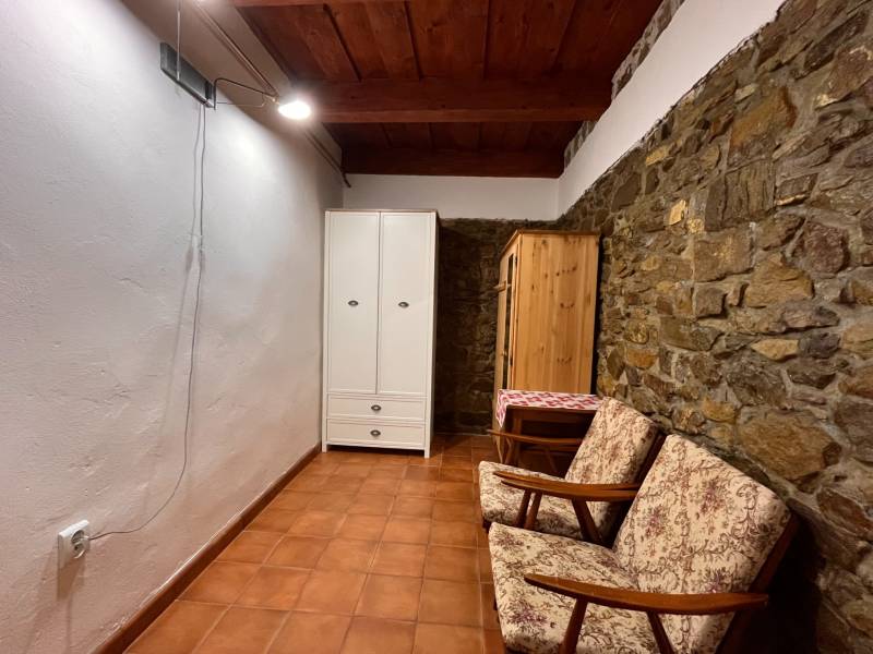 Steinwand, zwei Sessel, weißer und hölzerner Kleiderschrank, Keramikboden.