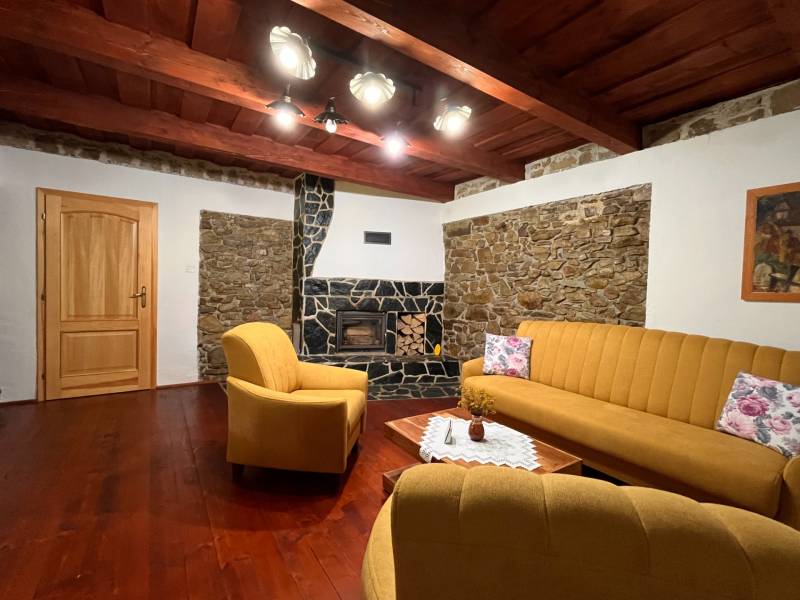 Wohnzimmer in einem Einfamilienhaus mit einem Steinkamin, gelben Sofas und Holzboden.