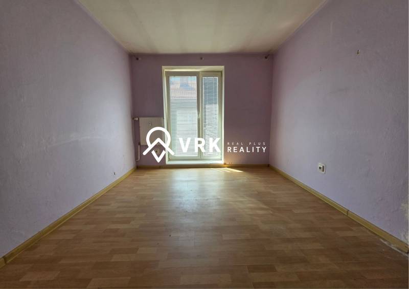 Ein Zimmer mit lila Wänden und Holzboden in einer 2-Zimmer-Wohnung.