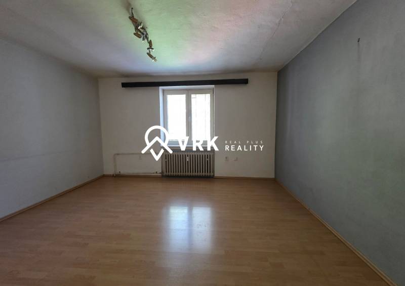 Ein leerer Raum mit Parkettboden und einem Fenster in einer 2-Zimmer-Wohnung.