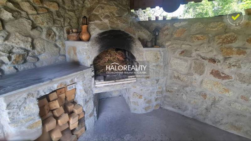 Ein steinerner Kamin im Inneren eines Einfamilienhauses, umgeben von Holz und Keramikdekorationen.