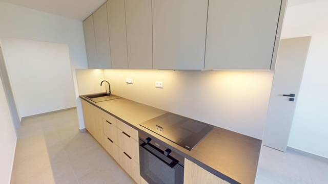 Küche in einer 2-Zimmer-Wohnung mit moderner Arbeitsplatte und eingebauten Geräten.