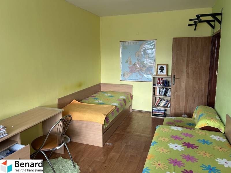 Ein Zimmer in einer 2-Zimmer-Wohnung mit Betten, einem Schreibtisch und einem Bücherregal.