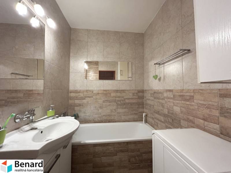 Badezimmer in einer 2-Zimmer-Wohnung mit Badewanne, Waschbecken und Fliesen in neutralen Tönen.