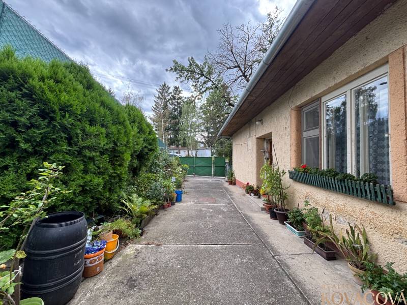 Ein Einfamilienhaus in Ilava mit Fensterblumen, einem angrenzenden Garten und einem Betonnadvorie.