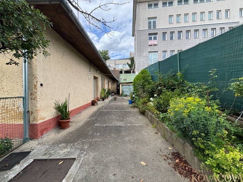 Das Äußere eines Einfamilienhauses in Ilava mit einer Gasse und Blick auf ein höheres Gebäude.