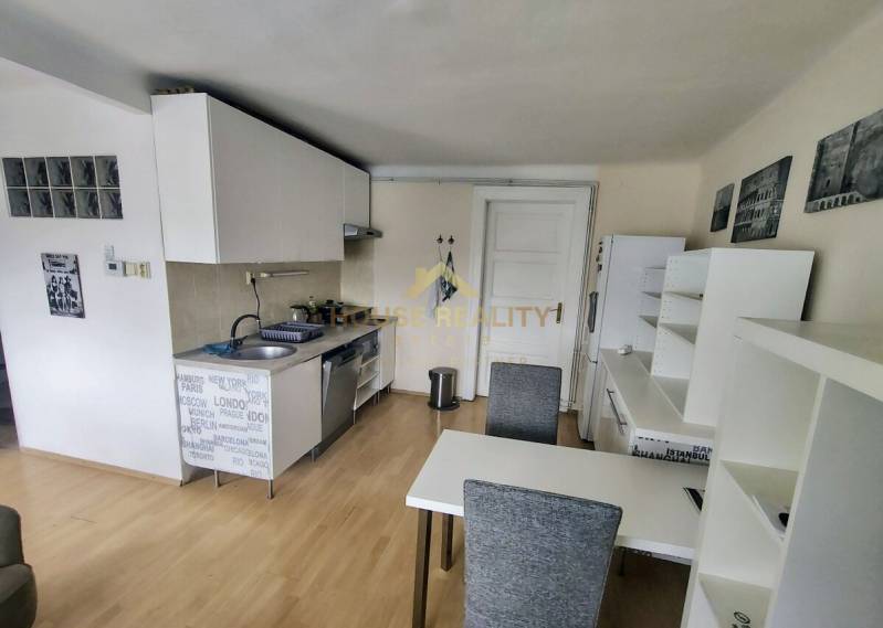 Küche in einer 2-Zimmer-Wohnung mit Esstisch, weißen Schränken und Holzboden.