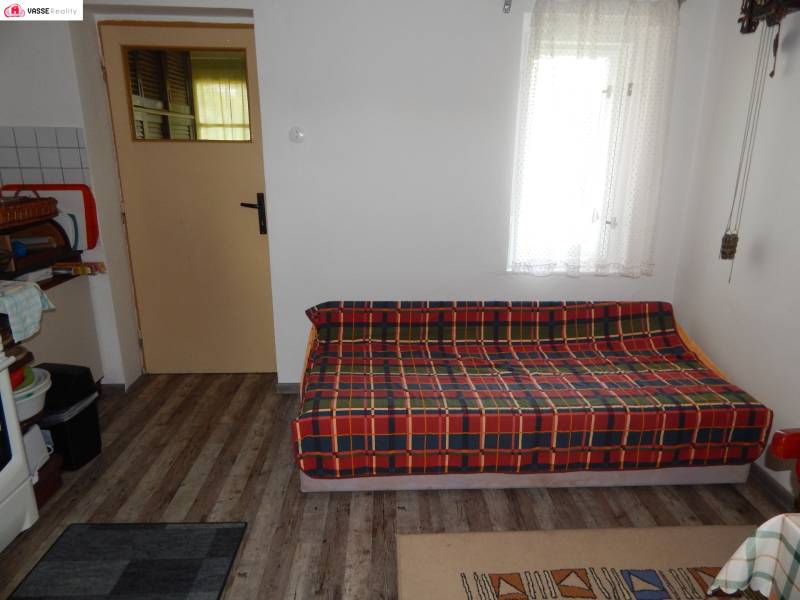 Chata mit einem bequemen Sofa, einem Teppich und einer Tür, die in einen weiteren Raum führt.