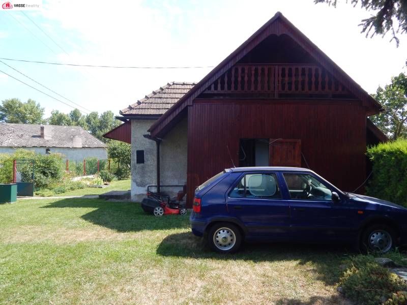 Ein Auto geparkt bei der Hütte in Klížska Nemá, umgeben von grünem Rasen und Bäumen.