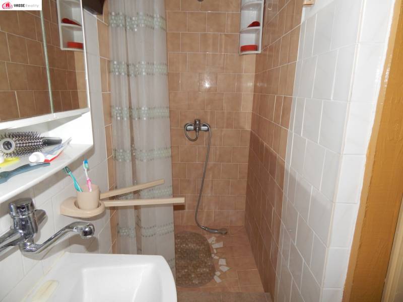 Ein Badezimmer in einer Hütte mit braunen Fliesen, einer Dusche und einem Waschbecken.
