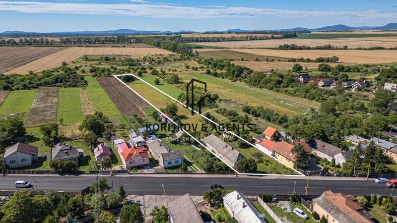 Grundstücke zum Wohnen in Sečovce, grüne Felder, einige Häuser und eine große Straße vorne.