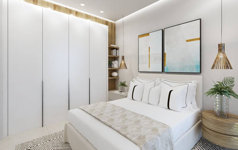 Helles Schlafzimmer in einer 3-Zimmer-Wohnung mit weißen Schränken und bunten Bildern.