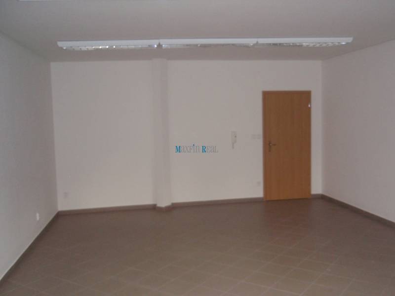 Leerer Büroraum mit braunen Fliesen und Holztüren.