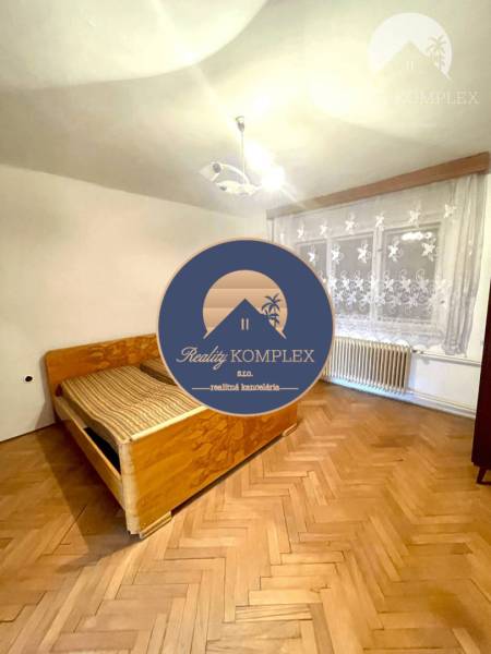 Das Innere eines Einfamilienhauses mit Holzboden, Bett und Vorhängen am Fenster.