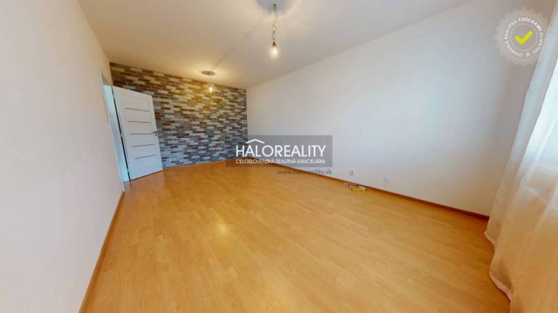 Ein Zimmer in einer 4-Zimmer-Wohnung mit Parkettboden und dekorativer Ziegelwand.
