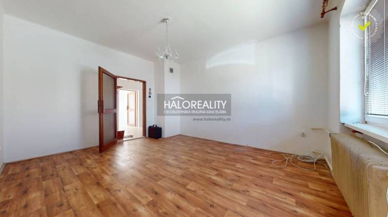 Geräumiges Zimmer mit Holzboden, Kronleuchter und offenen Türen in einem Einfamilienhaus.