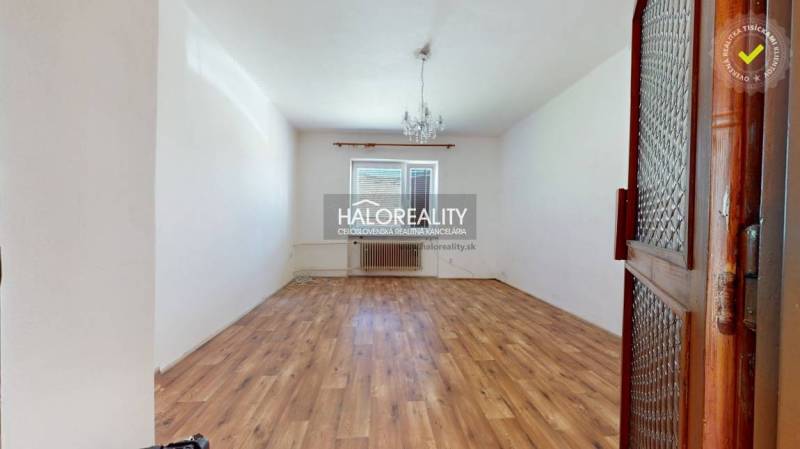 Ein leerer Raum mit Holzboden und einem Kronleuchter in einem Einfamilienhaus.