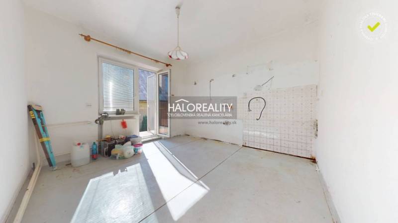 Ein leerer Raum in einem Einfamilienhaus mit Terrassentüren und Vorbereitung für eine Küche.