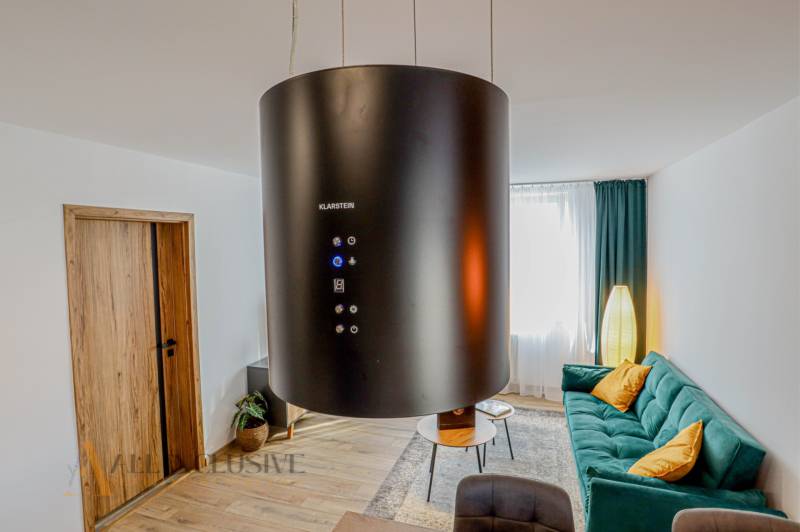 Wohnzimmer mit Kronleuchter, grünem Sofa und dekorativen Kissen in einer 3-Zimmer-Wohnung.