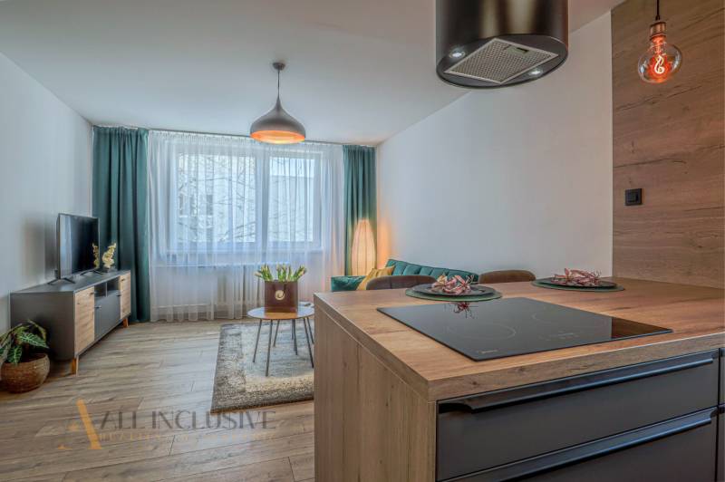 Wohnzimmer in einer 3-Zimmer-Wohnung mit Kücheninsel, Fernseher und Sofa.