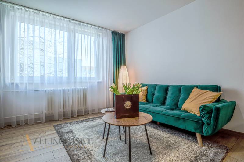 Wohnzimmer in einer 3-Zimmer-Wohnung mit Sofa, Tisch und Blumen, helle Atmosphäre.