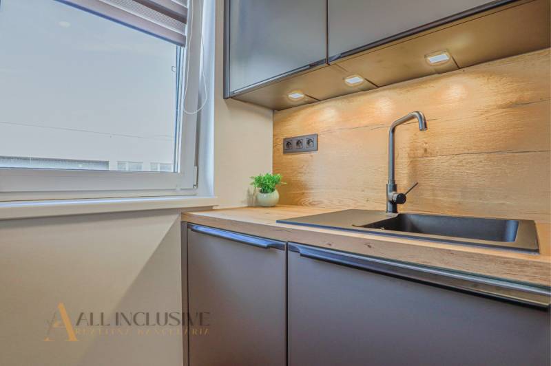 Küche in einer 3-Zimmer-Wohnung mit schwarzem Spülbecken und Holzarbeitsplatte.